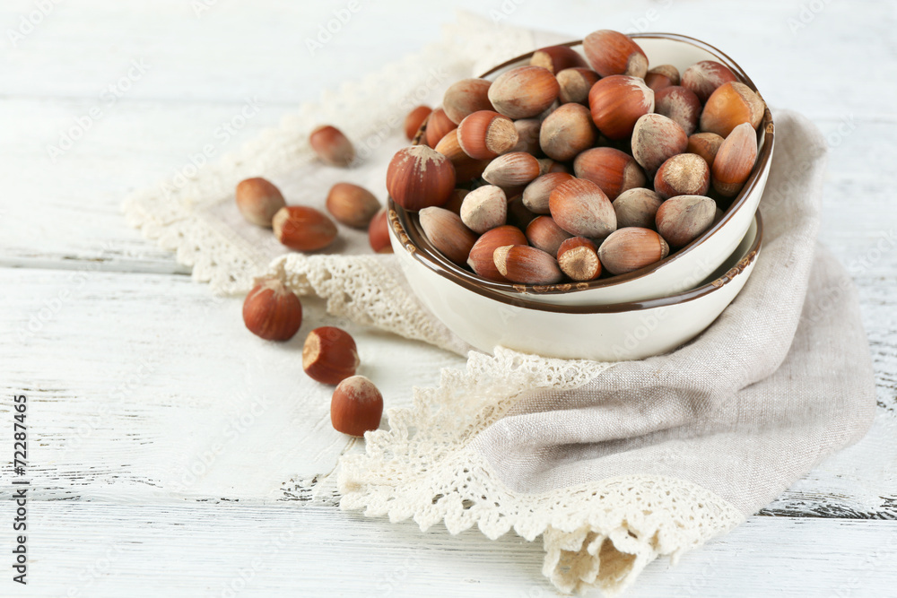 Hazelnuts on plate on napkin on wooden background Hazelnuts on plate on napkin on wooden background