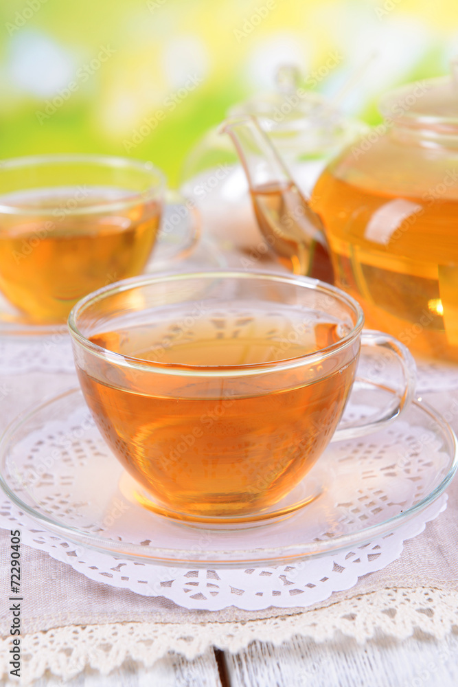 Teapot and cups of tea on table on bright background Teapot and cups of tea on table on bright background