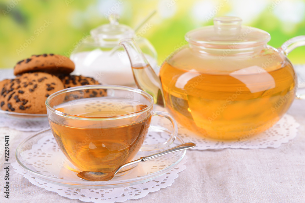 Teapot and cup of tea on table on bright background Teapot and cup of tea on table on bright background
