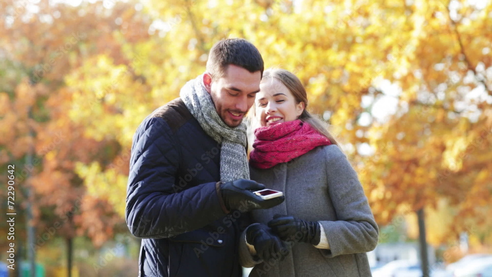 smiling couple with smartphone in autumn park smiling couple with smartphone in autumn park