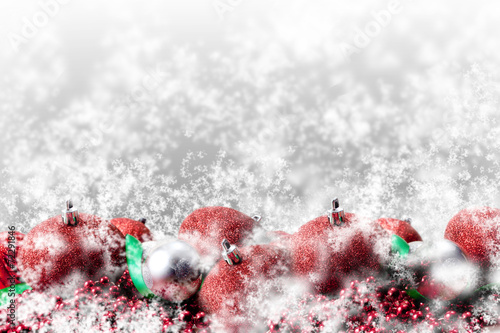 red christmas ornaments and green ribbon in snow