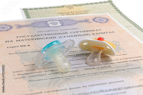 Two baby's dummies with maternal and birth certificates isolated