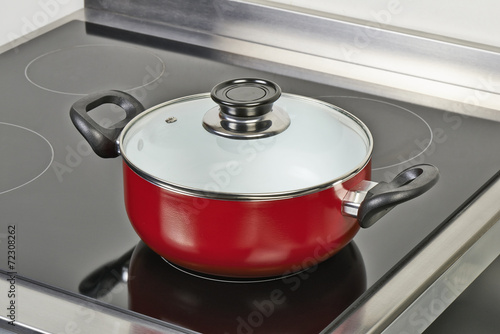 Red ceramic pan with cover on Electric hob
