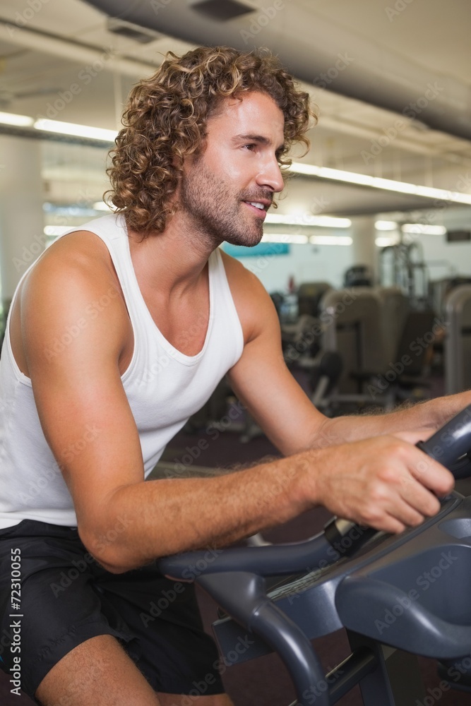 Side view of man working out on exercise bike at gym Side view of man working out on exercise bike at gym