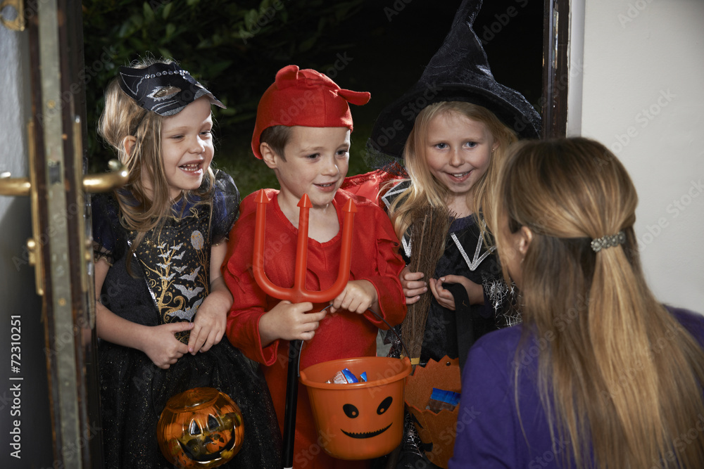 Halloween Party With Children Trick Or Treating In Costume - obrazy, fototapety, plakaty 