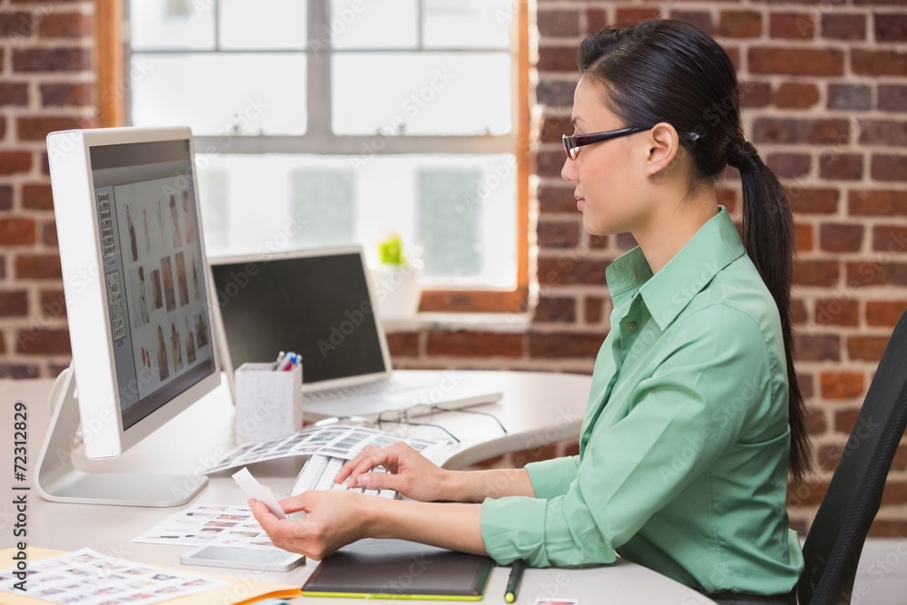 Concentrated female photo editor using computer in office Concentrated female photo editor using computer in office