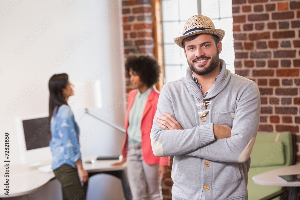 Fototapeta premium Man with arms crossed and colleagues behind in office