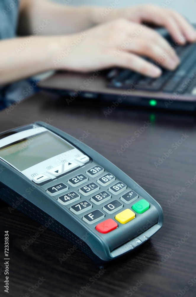 Payment terminal in the office. Man working with laptop in the b Payment terminal in the office. Man working with laptop in the b