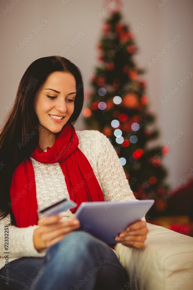 Pretty brunette shopping online with tablet at christmas Pretty brunette shopping online with tablet at christmas