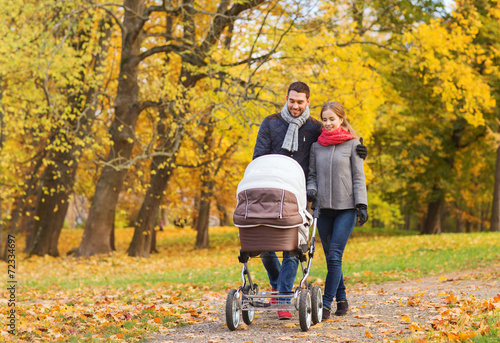smiling couple with baby pram in autumn park