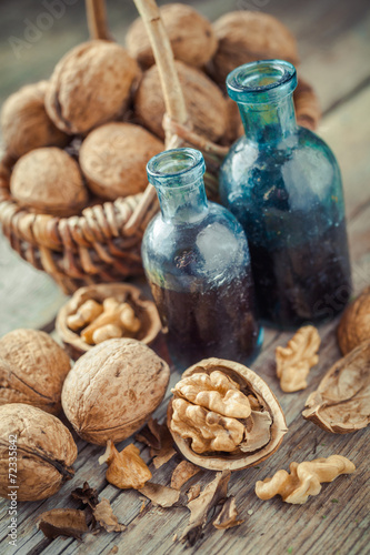 Walnuts in basket and nuts tincture or oil on old table
