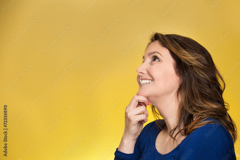 Closeup thoughtful happy woman looking up on yellow background Closeup thoughtful happy woman looking up on yellow background