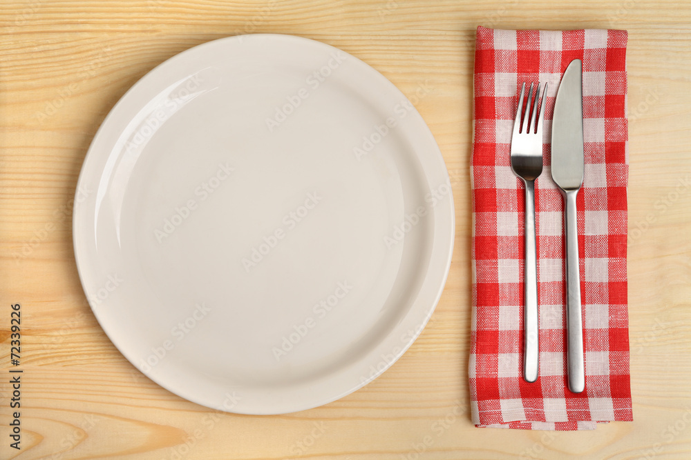 Empty plate with cutlery on red napkin on wooden background. Empty plate with cutlery on red napkin on wooden background.