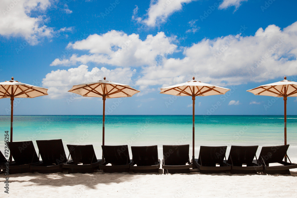 Turquoise sea, deckchairs, white sand and beach umbrellas. Calmn