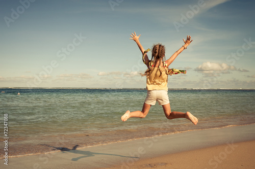 teen girl jumping on the beach at the day time
