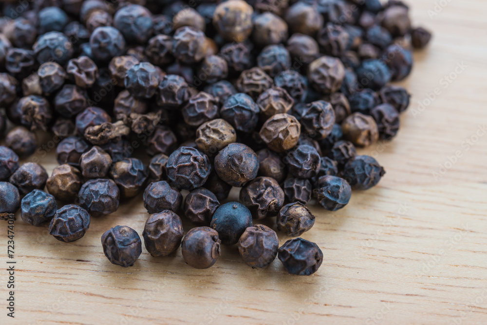 Obraz premium Black pepper on wood background