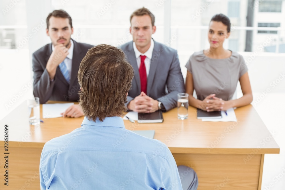 Business people interviewing man in office Business people interviewing man in office