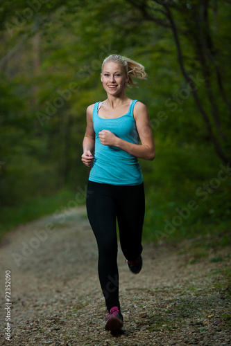 Fototapeta Naklejka Na Ścianę i Meble -  beautiful young woman runs in forest - active runner running