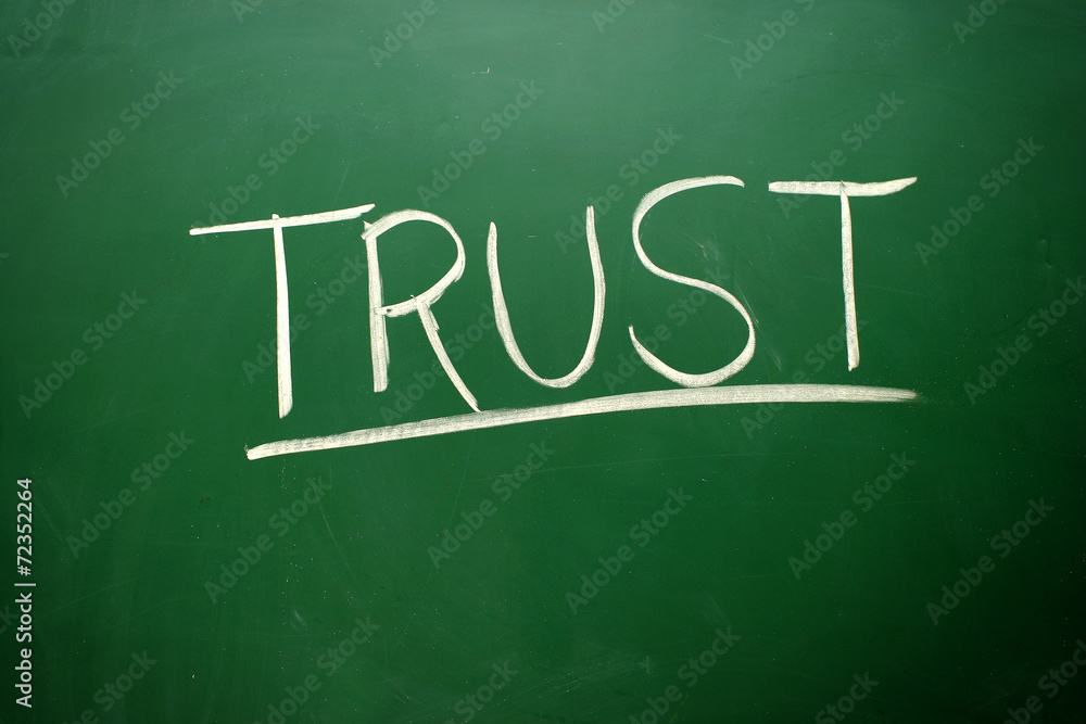 Handwritten Trust word with white chalk on a blackboard Handwritten Trust word with white chalk on a blackboard