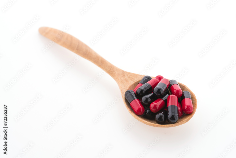 Tablet pill on wood spoon isolated on white background Tablet pill on wood spoon isolated on white background