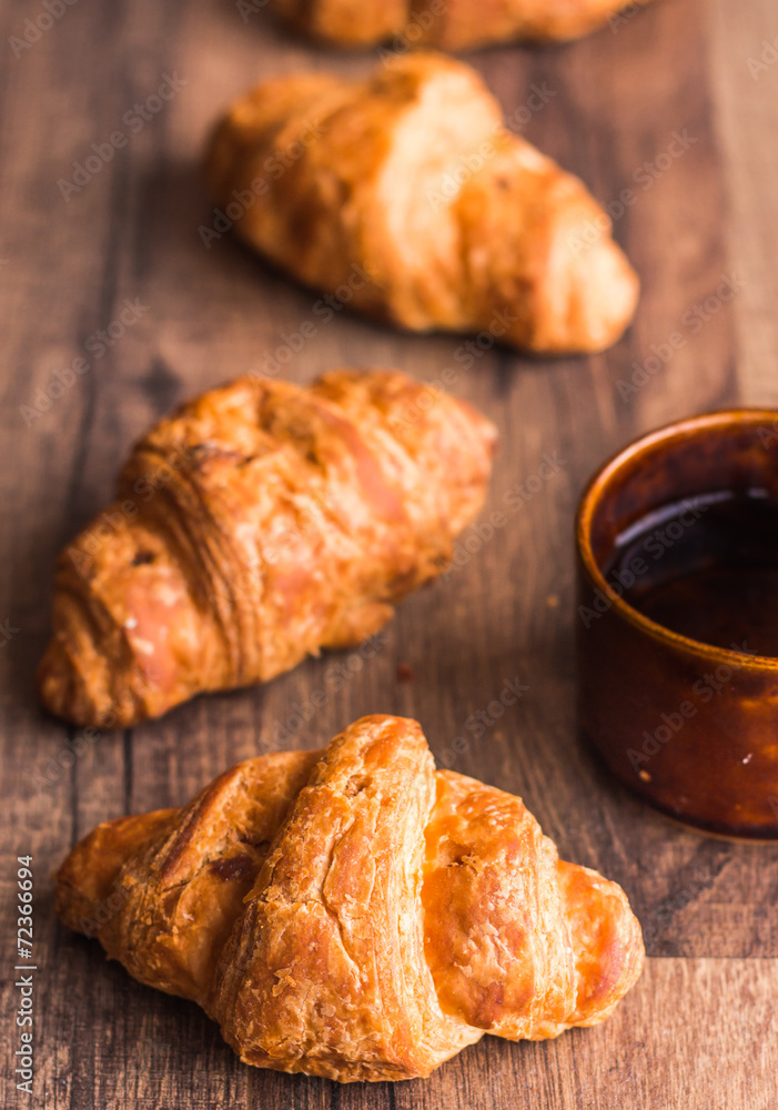croissant with chocolate on a wooden board, coffee cup