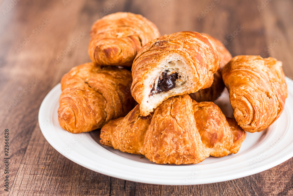 bite croissants with chocolate on a white plate, breakfast