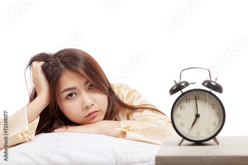 Sleepy Asian girl  wake up  with pillow and alarm clock