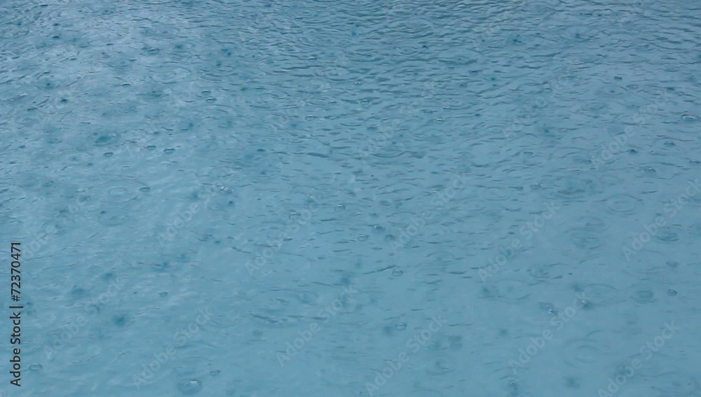 Regentropfen fallen in Swimmingpool im Urlaub Regentropfen fallen in Swimmingpool im Urlaub