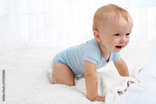 Cute baby boy on bed in room