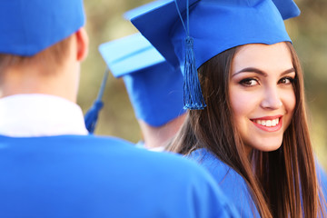 Graduate students wearing graduation hat and gown, outdoors