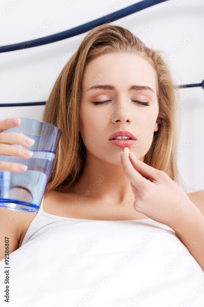 Naklejka premium Woman taking pills in bed