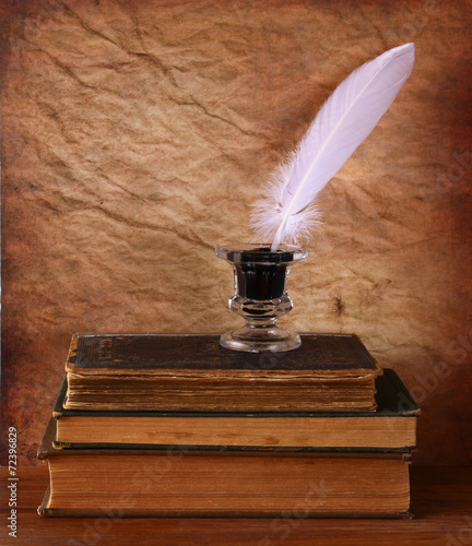 Fotografia low key image of white Feather, inkwell and ancient books on old