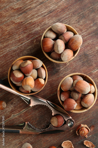 Hazelnuts in wooden bowls, on napkin on wooden background