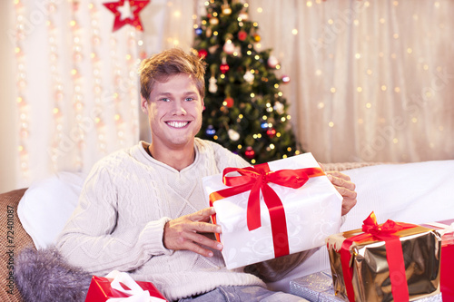 Glücklicher junger Mann mit Geschenken an Weihnachten