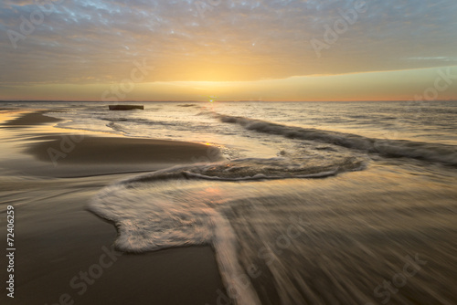 fale przelewający się na plaży morskiej podczas zachodu słońca
