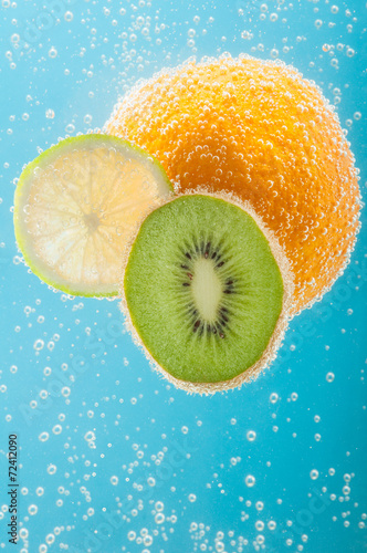 Fototapeta Naklejka Na Ścianę i Meble -  Orange, kiwi and lime in water with bubbles.