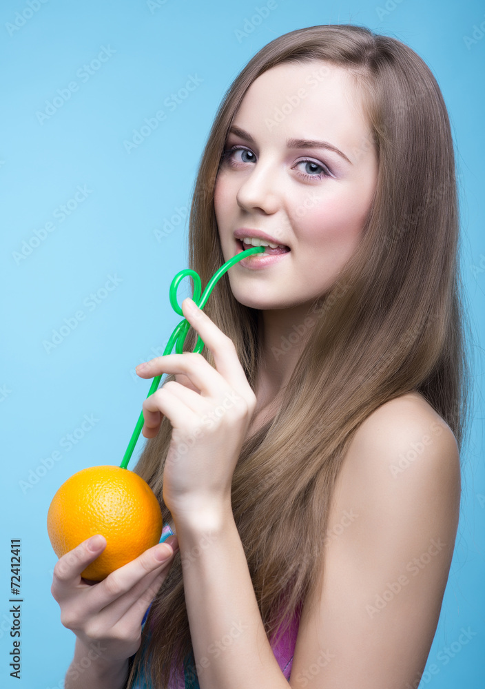 beautiful girl drinking orange juice through a straw