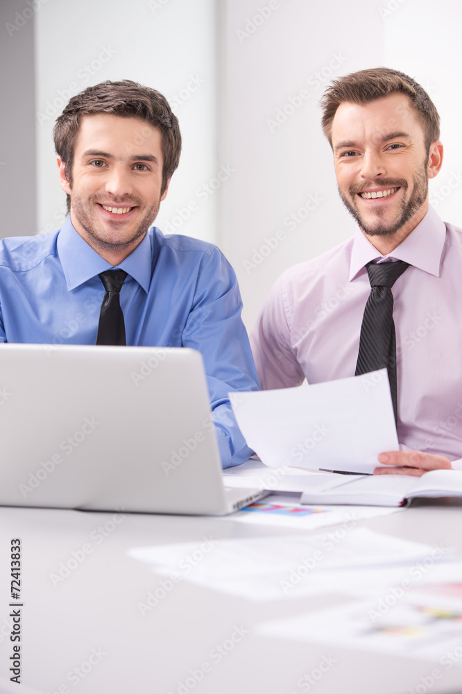 Fototapeta premium Two business men working together on laptop in office.
