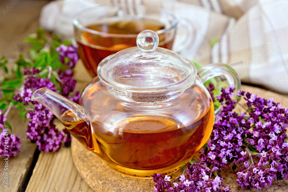 Tea of oregano in glass teapot on board with cup Tea of oregano in glass teapot on board with cup