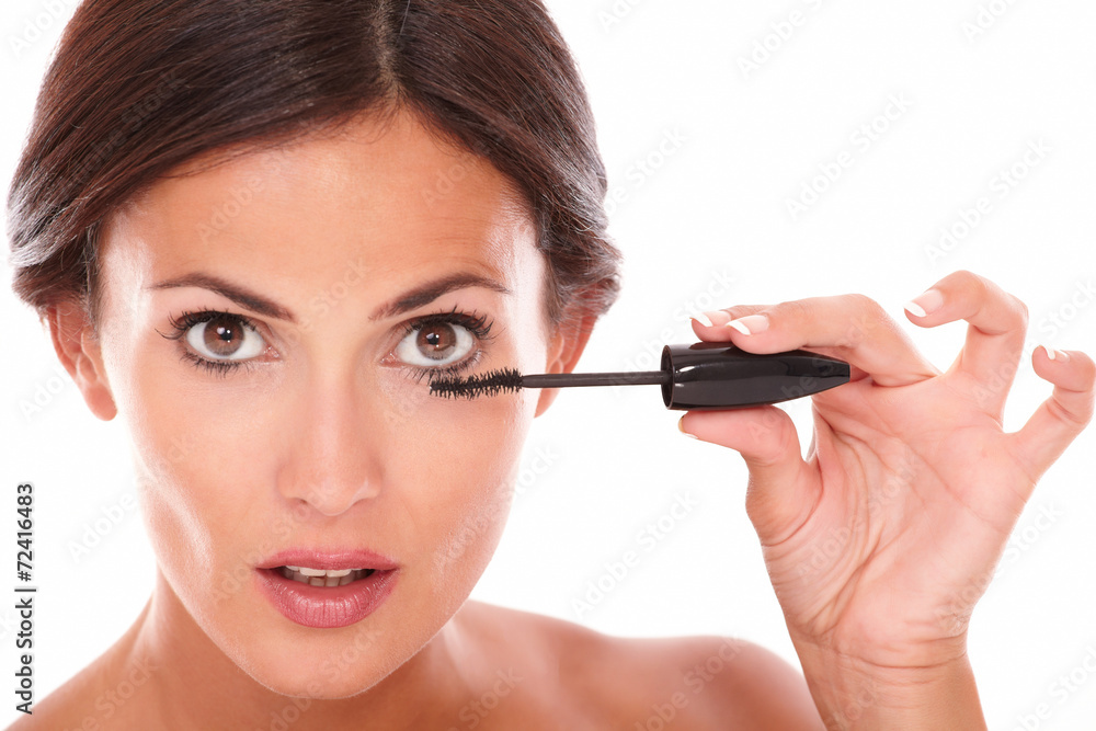 Afraid woman with brown eyes applying mascara Afraid woman with brown eyes applying mascara