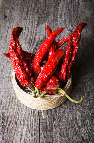 bunch of red hot peppers lying in a wicker basket on old wooden