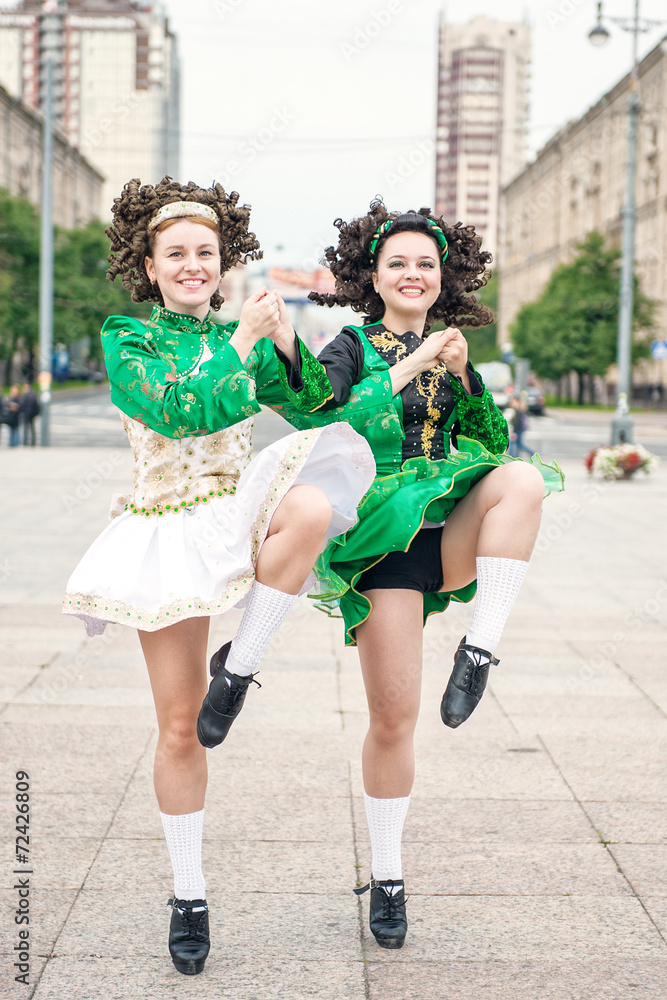 Obraz premium Two women in irish dance dresses and wig dancing