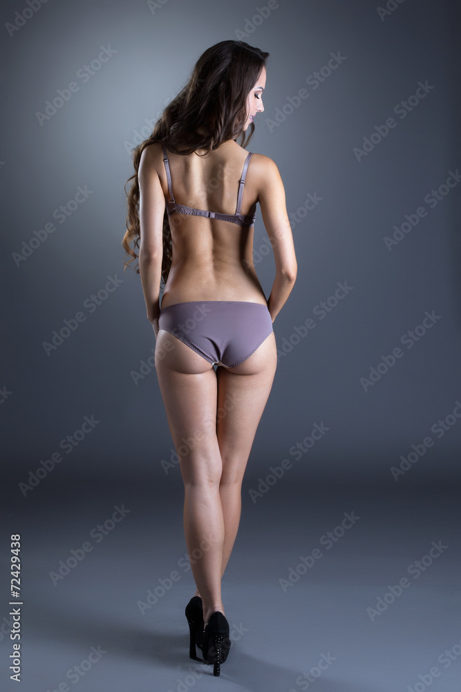 Rear view of slender woman posing in lingerie
