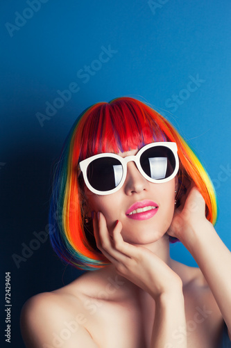 beautiful woman wearing colorful wig and white sunglasses agains