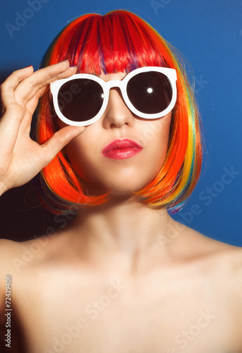 beautiful woman wearing colorful wig and white sunglasses agains