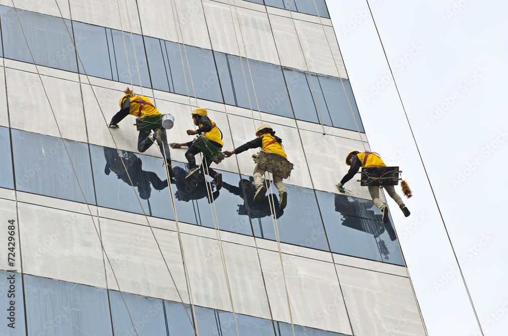 group of workers cleaning windows on high rise building