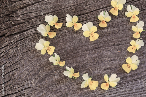 yellow flowers in form heart on wooden background