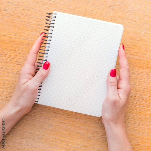 Woman hand holding notebook on wooden background