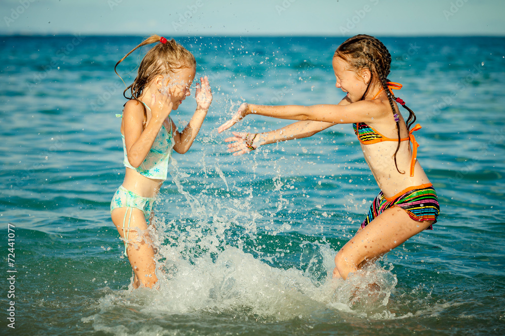 Happy little girls playing at the beach at the day time