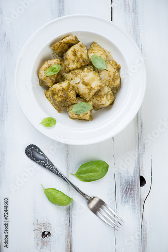 Ravioli with basil pesto, rustic wooden background, above view